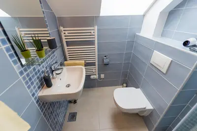 a blue tiled bathroom with a toilet and a sink at Central Apartments with Parking in Ljubljana