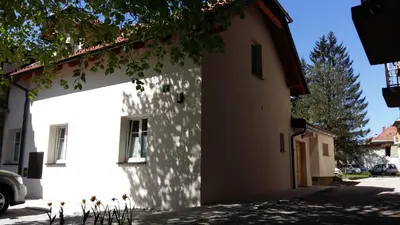 a white building with a tree shadow on it at Central Apartments with Parking in Ljubljana