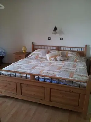 a large bed with a wooden frame in a bedroom at Apartments Mali Raj in Dolenci