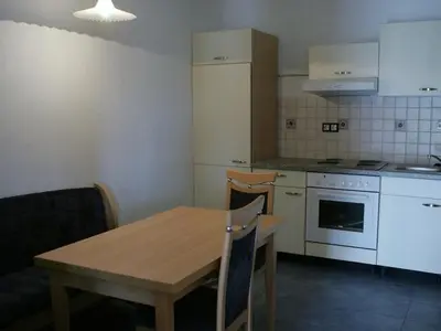 a kitchen with a wooden table and a kitchen with white appliances at Apartments Mali Raj in Dolenci