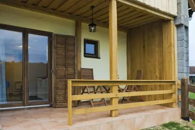 a porch of a house with a wooden bench at Apartments Mali Raj in Dolenci