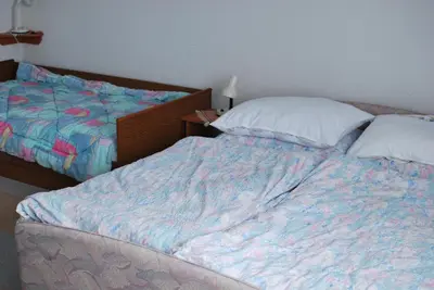 an unmade bed in a bedroom next to a bedskirtspectspects at Farm Stay Bogša in Ormoz
