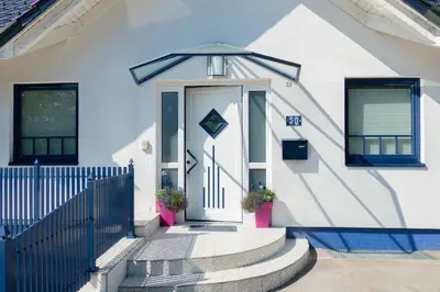 a white house with a blue fence and a door at Modrin Apartments in Kamnik