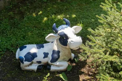 a statue of a cow laying on the grass at Modrin Apartments in Kamnik
