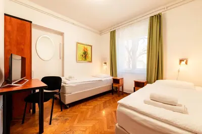 a hotel room with two beds and a desk at Penzion Pod Lipo in Ljubljana