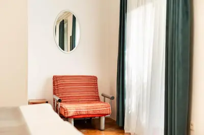 a chair in a room with a mirror and a window at Penzion Pod Lipo in Ljubljana