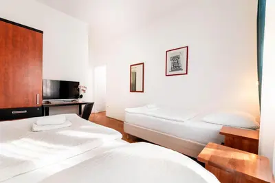 a bedroom with two beds and a tv in it at Penzion Pod Lipo in Ljubljana