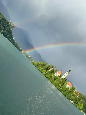 a rainbow on the side of a lake with houses at Boomerang Apartment Bled in Bled