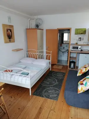 a bedroom with a white bed and a kitchen at Peter rooms in Ljubljana