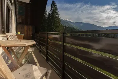 a wooden table and chairs on a balcony with mountains at Apartment Amazing View in Bohinj