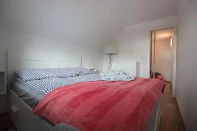 a white bedroom with a bed with a red blanket at Apartment Amazing View in Bohinj