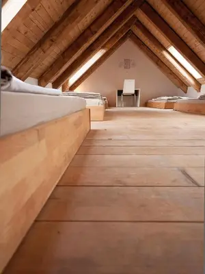 an attic room with beds and a table at Hostel Situla in Novo Mesto
