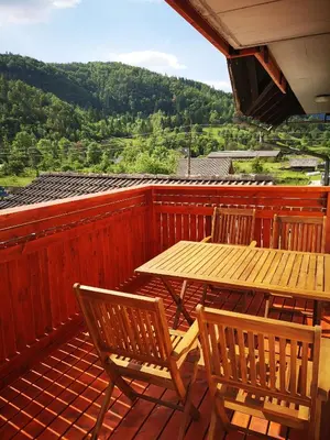 a wooden deck with a wooden table and chairs at Apartmaji Hodak in Bohinj