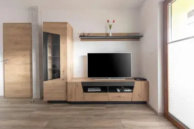 a living room with a television on a wooden entertainment center at Apartmaji Hodak in Bohinj