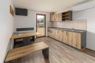 a kitchen with wooden cabinets and a table and a sink at Apartmaji Hodak in Bohinj