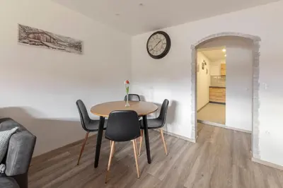 a table and chairs in a room with a clock on the wall at Apartmaji Hodak in Bohinj