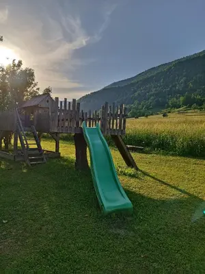 a playground with a green slide in a field at Apartmaji Hodak in Bohinj