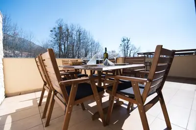 a table and chairs on a balcony with a bottle of wine at Apartment Tiara 2 in Rodine