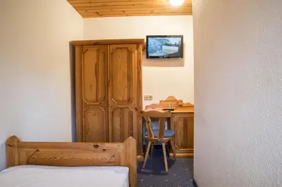 a bedroom with a wooden cabinet and a desk with a chair at Garni Hotel Berc in Bled
