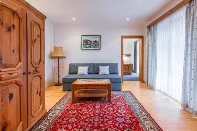 a living room with a blue couch and a red rug at Garni Hotel Berc in Bled