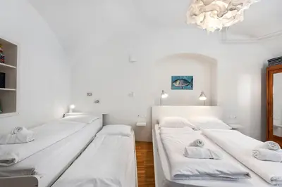 three beds in a room with white walls and a chandelier at ROG Apartment with Furnished Courtyard in Ljubljana