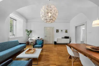 a living room with a blue couch and a chandelier at ROG Apartment with Furnished Courtyard in Ljubljana