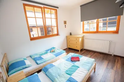 a bedroom with two beds and a dresser and two windows at BikeSki family hotel, b&b, apartaments, rooms in Mežica