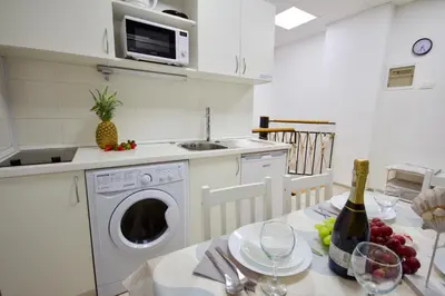 a kitchen with a washing machine and a table with wine glasses at Blue Point Apartment Ljubljana in Ljubljana