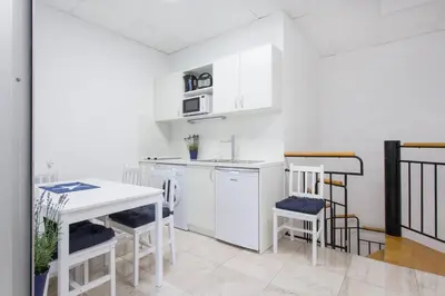 a kitchen with white cabinets and a table and chairs at Blue Point Apartment Ljubljana in Ljubljana