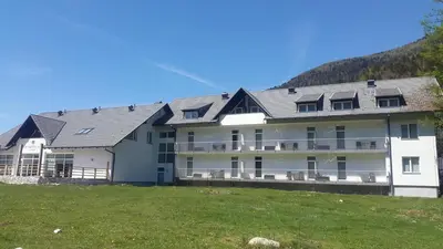 a large white building with a hill in the background at klass 203 in Kranjska Gora