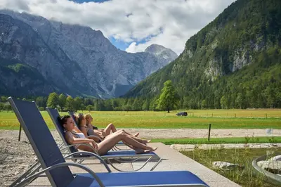 two girls sitting in lounge chairs on a beach at Hotel Plesnik Logar Valley in Solčava