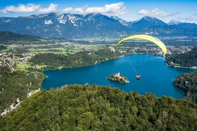 a paraglider flying over a lake with mountains at Sky in Bled