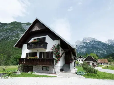 a house with flowers on the balcony and mountains at Apartments and rooms Nataša 2 in Trenta
