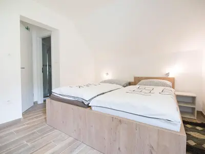 a large wooden bed in a room with white walls at Apartments and rooms Nataša 2 in Trenta