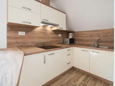 a kitchen with white cabinets and a wooden wall at Apartments and rooms Nataša 2 in Trenta