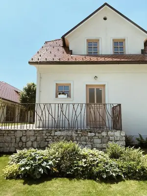 a white house with a fence and some bushes at Tri lučke Hotel & Restaurant in Krško