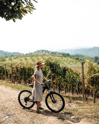 a woman standing next to a bike in a vineyard at Tri lučke Hotel & Restaurant in Krško