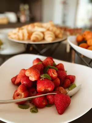 a plate of strawberries on a table with plates of pastries at Tri lučke Hotel & Restaurant in Krško
