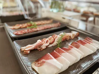 a buffet line with meats and bacon on trays at Tri lučke Hotel & Restaurant in Krško