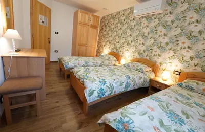 a hotel room with three beds and a desk at Domačija Bubec in Ilirska Bistrica
