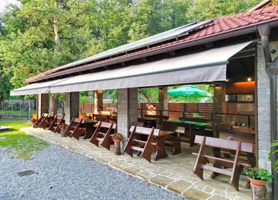 a patio with wooden tables and chairs under a pavilion at Domačija Bubec in Ilirska Bistrica