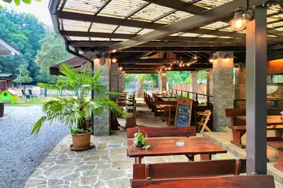 a restaurant with wooden tables and chairs and a patio at Domačija Bubec in Ilirska Bistrica