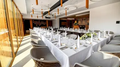 a long banquet room with white tables and chairs at Hotel Ajdovec in Sevnica