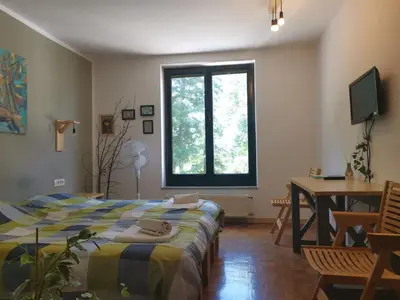 a bedroom with a bed and a desk and a window at Guest House Park Žibert in Ljubljana