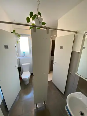 a bathroom with white stalls and a toilet and a sink at Guesthouse GreenSLO in Ljubljana