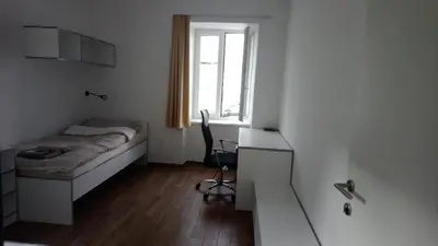 a bedroom with a bed and a desk and a window at Bajta na obzidju in Maribor