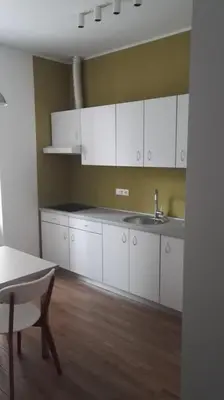 a kitchen with white cabinets and a sink and a table at Bajta na obzidju in Maribor