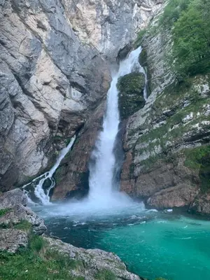 a waterfall on the side of a mountain with green water at Holiday house Jereka -Bohinj in Bohinj
