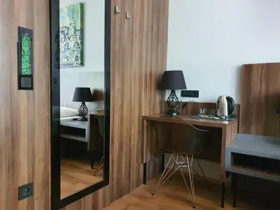 a mirror in a room with a desk and a bed at Atelier Hotel in Ljubljana