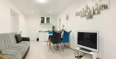 a living room with a couch and a tv and a table at Lina Rooms Hostel in Ljubljana